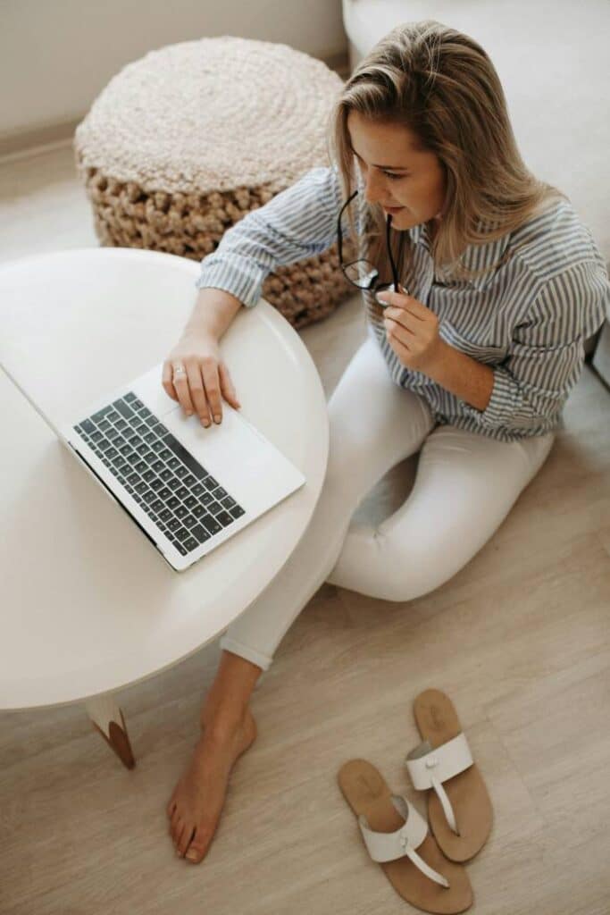 woman sitting on floor looking at laptop that's sitting on a table